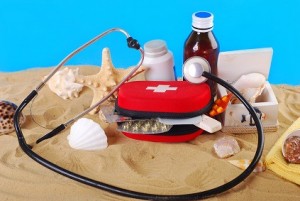 "first aid box with medicines,thermometer and stethoscope on the beach as healthy summer holiday concept"